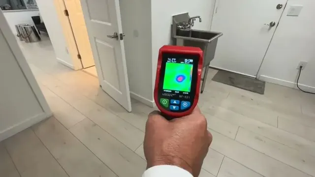 Hand holding a thermal imaging camera inside a room to find a hidden leak