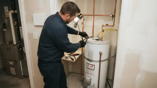 Plumber working on a tank water heater in a utility closet